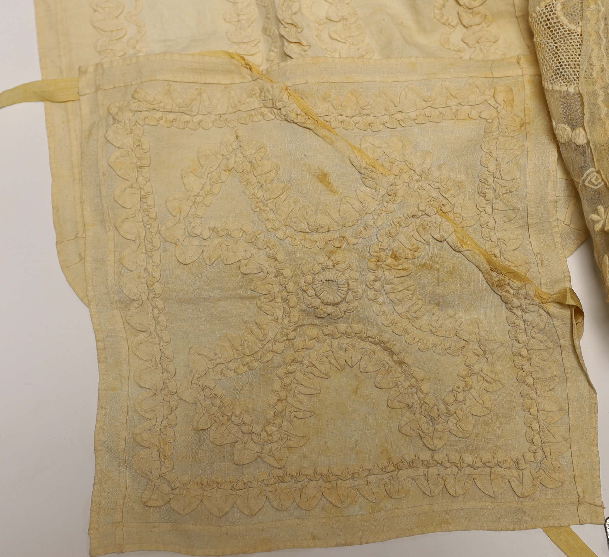 An 18th century Dresden worked apron, a white worked fine lawn stole, two panels of linen ribbon work, a ladies lace bonnet a similar pink satin bonnet a white worked blouse (partially made) and panel to a christening go